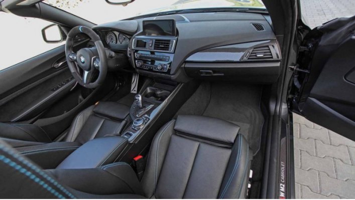 Интерьер открытой машины от купе BMW M2 отличается рулем с комбинированной отделкой, дополнительным…